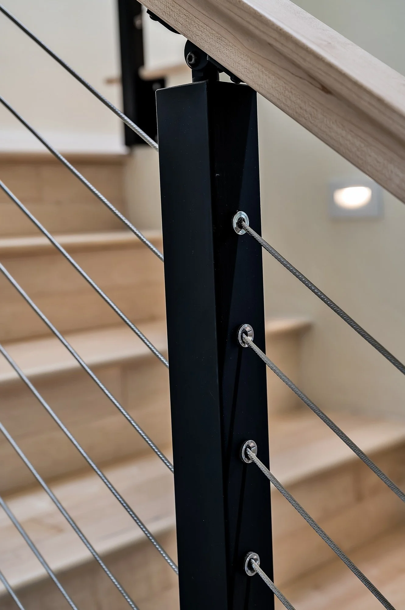 Stair railing connection detail in this Santa Cruz condo remodel, highlighting steel posts, tensioned cables, and clean attachment points.