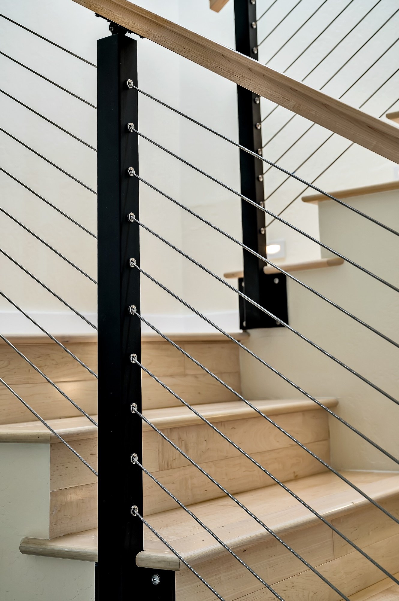 Cable railing detail in this Santa Cruz condo remodel, combining slim steel posts and horizontal cables to keep the stair visually open and light.