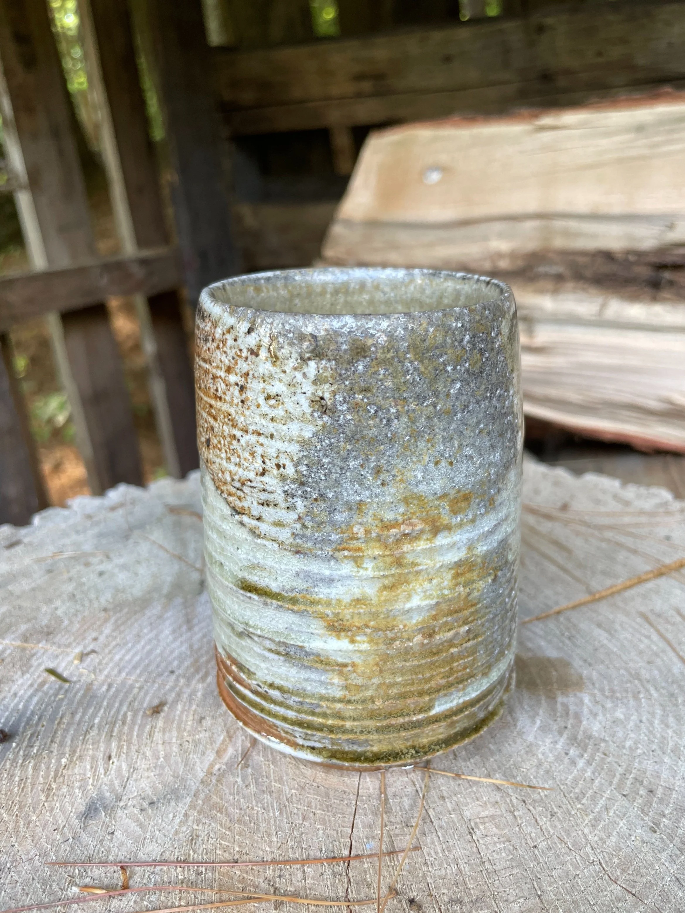A toasty clay cup with grayish-purple coloring from wood ash deposited during the firing