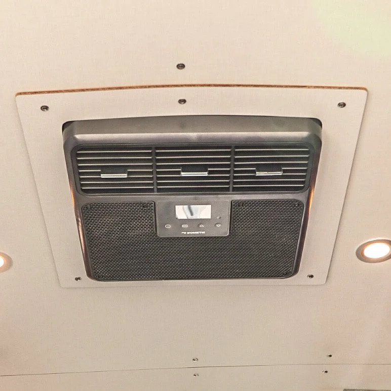 Ceiling air conditioning vent with adjustable vents and a control panel.