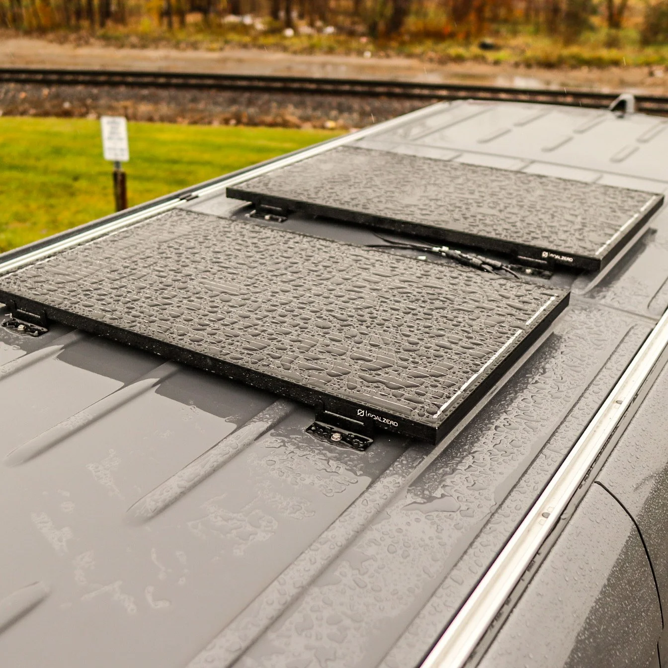 Rain droplets on two solar panels mounted on the roof of a vehicle.