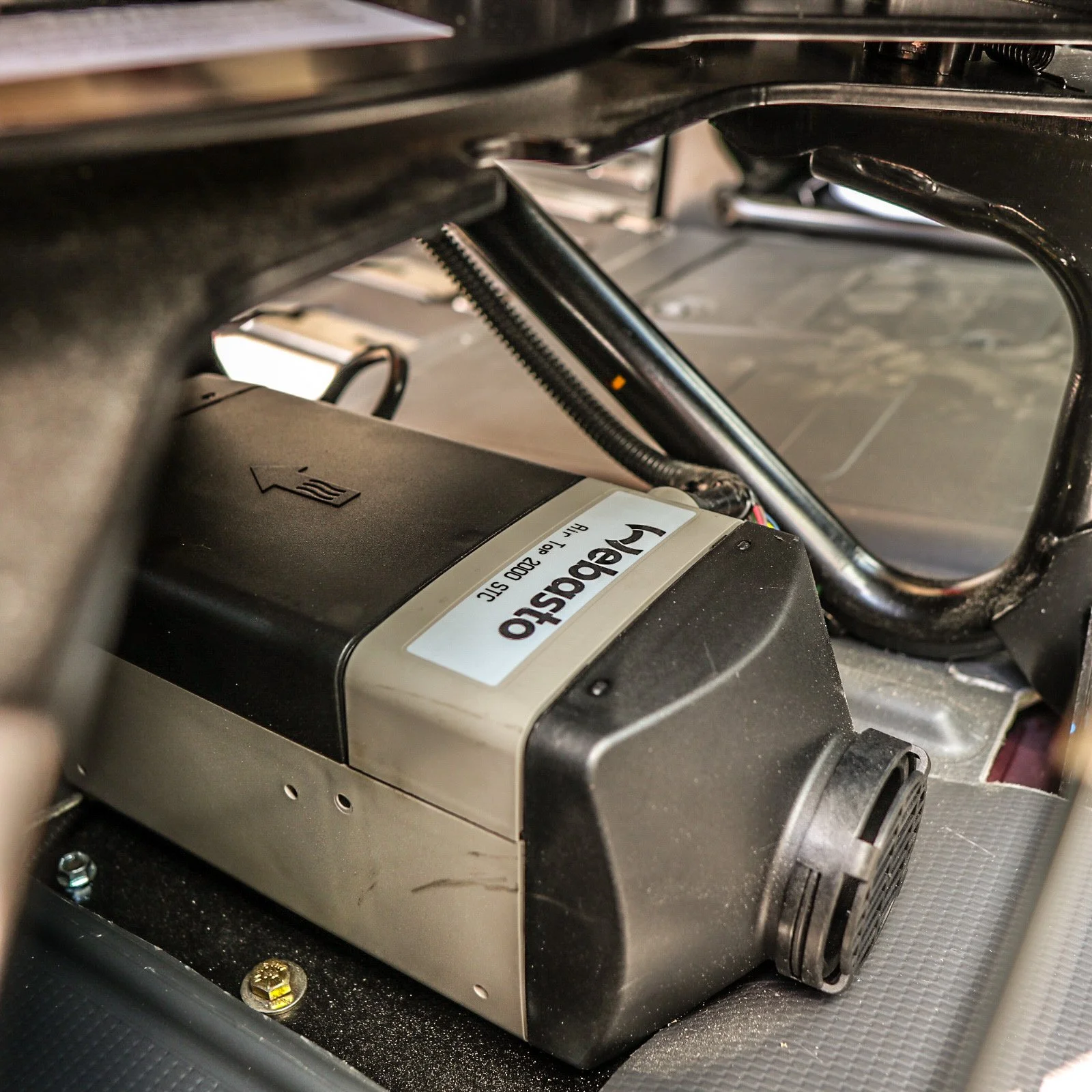 Close-up of a Velasto 2000 STC electric component inside a machine, with black and metallic parts, and a cable connected to it.