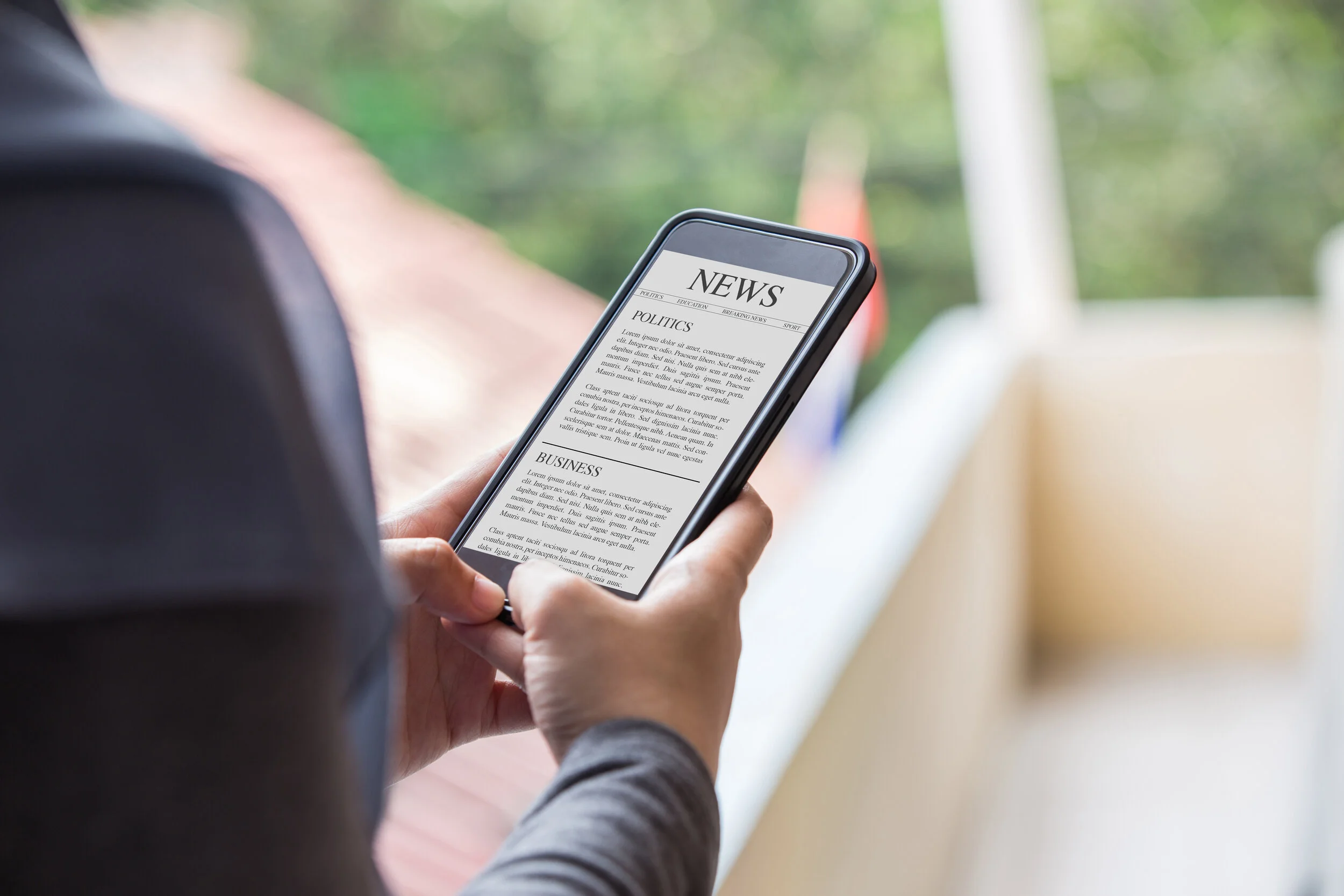 News article concept on phone screen. Woman hand holding smartphone reading news article on screen.