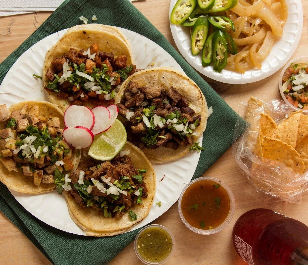 Plate of tacos with sides of chips and salsa, radish, lime, grilled onions and jalapeños from La Piñata in Vallejo