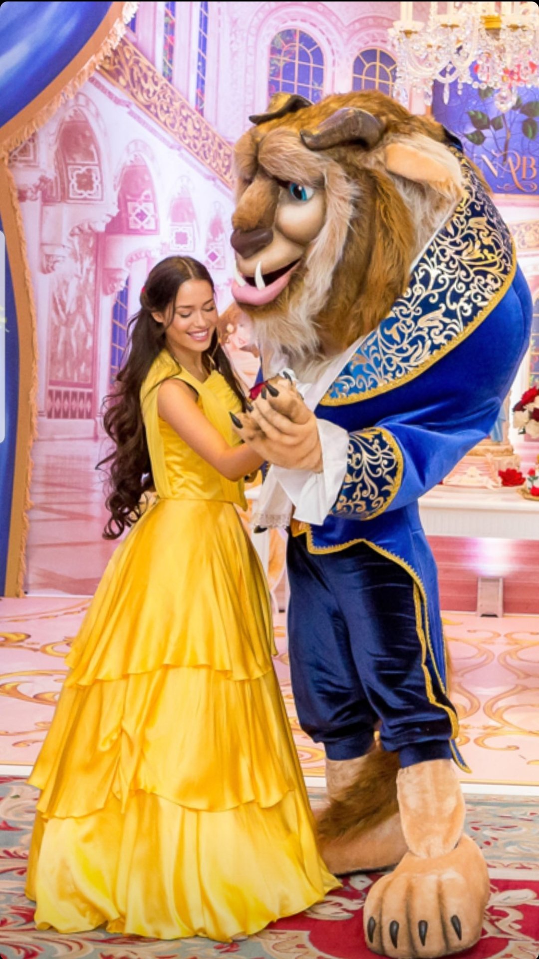 Woman in yellow dress dancing with Beast costume character from Beauty and the Beast at a themed event.