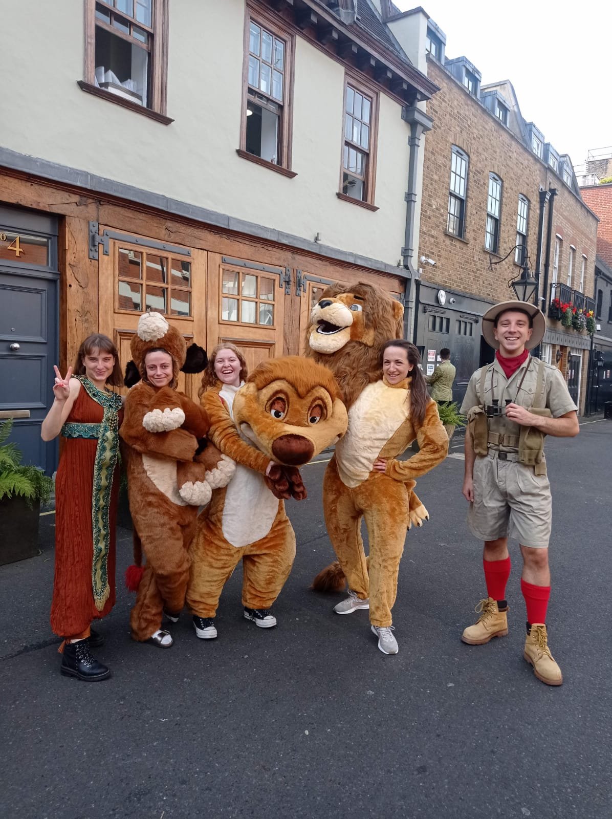 Group of people in animal costumes and jungle explorer outfit standing on a street.