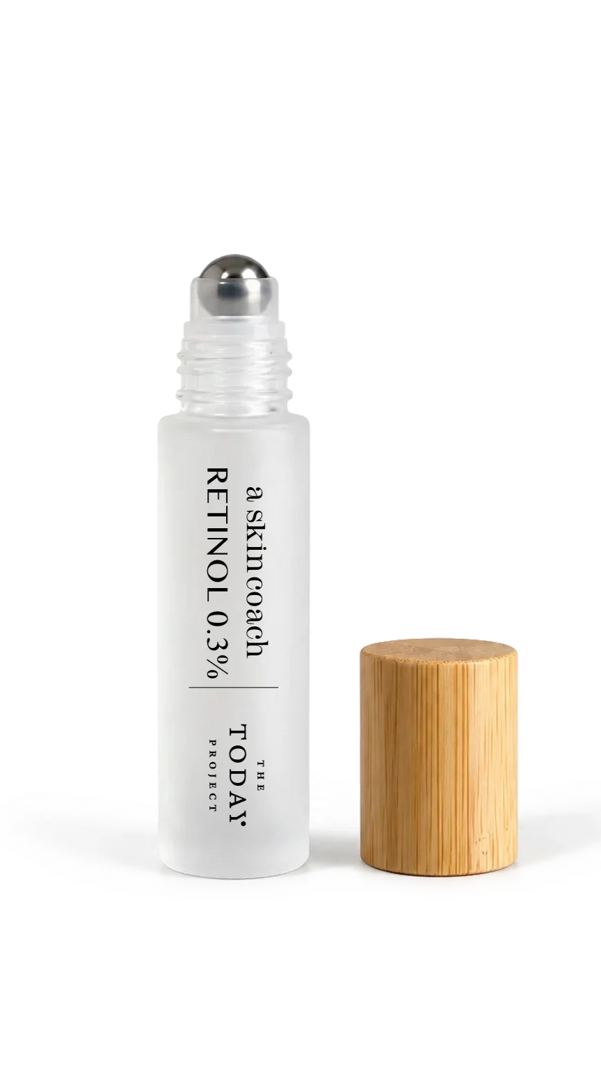 Un frasco de productos para el cuidado de la piel con la etiqueta «RETINOL 0,3 %» de la marca The Today Project , con un tapón de madera junto a él y una crema o loción blanca extendida debajo, sobre un fondo negro.