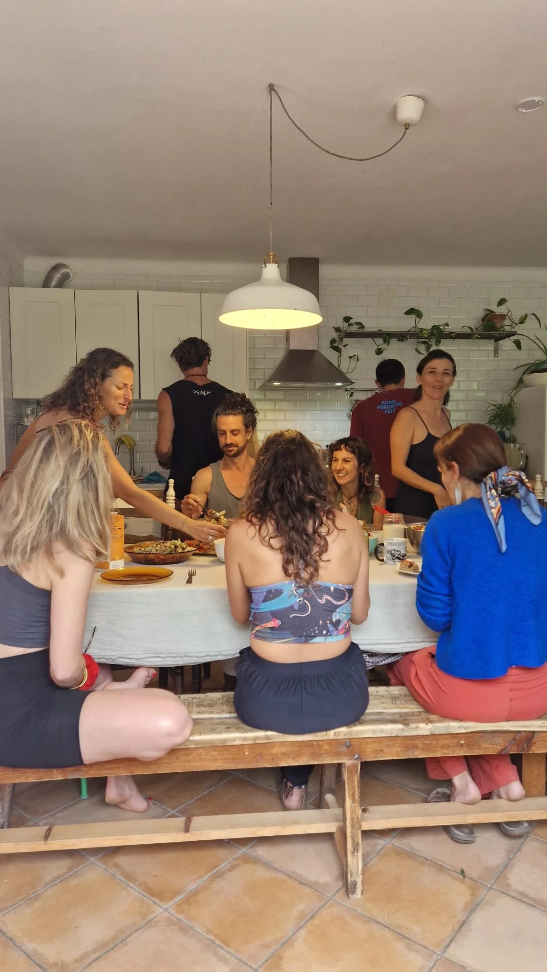 Grupo de personas disfrutando una comida en una cocina de estilo moderno, rodeadas de diferentes platos y sonrisas.