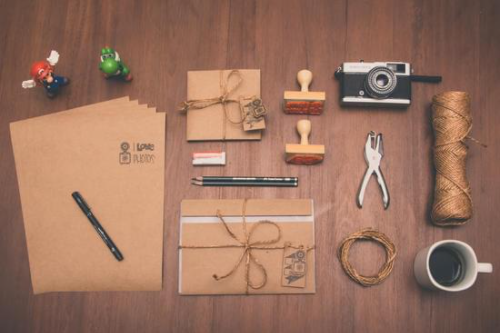 A careful arrangement of supplies including paper, envelopes, rubber stamps, a vintage camera, a mug of coffee and, crucially, Mario and Yoshi figurines.