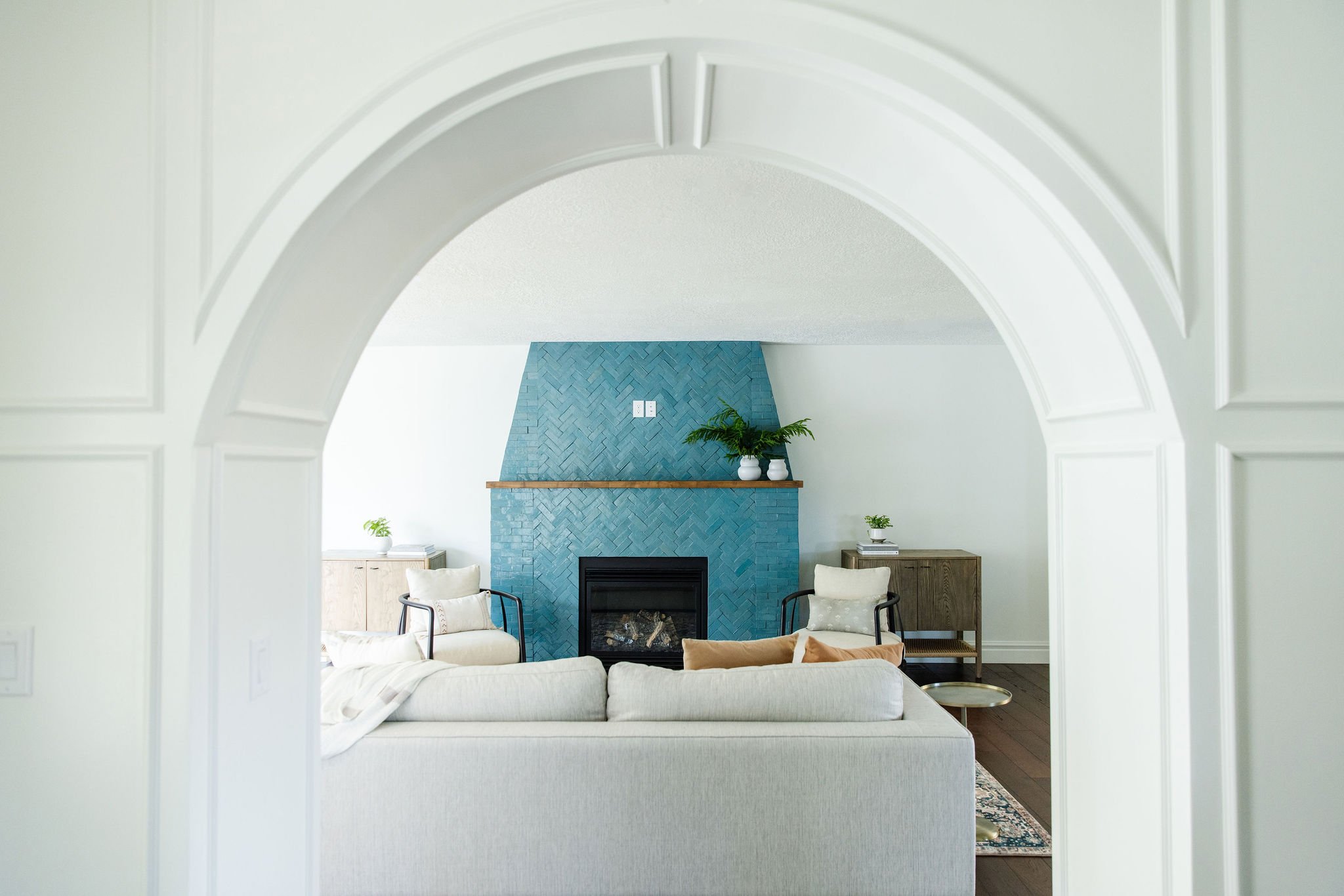  Detailed wainscot archway frames exquisite teal fireplace in a home designed by Liz Powell. teal fireplace arched entryway herringbone tile Logan Utah #tealfireplace #archeddoorway #wainscoting #livingroomdesign 
