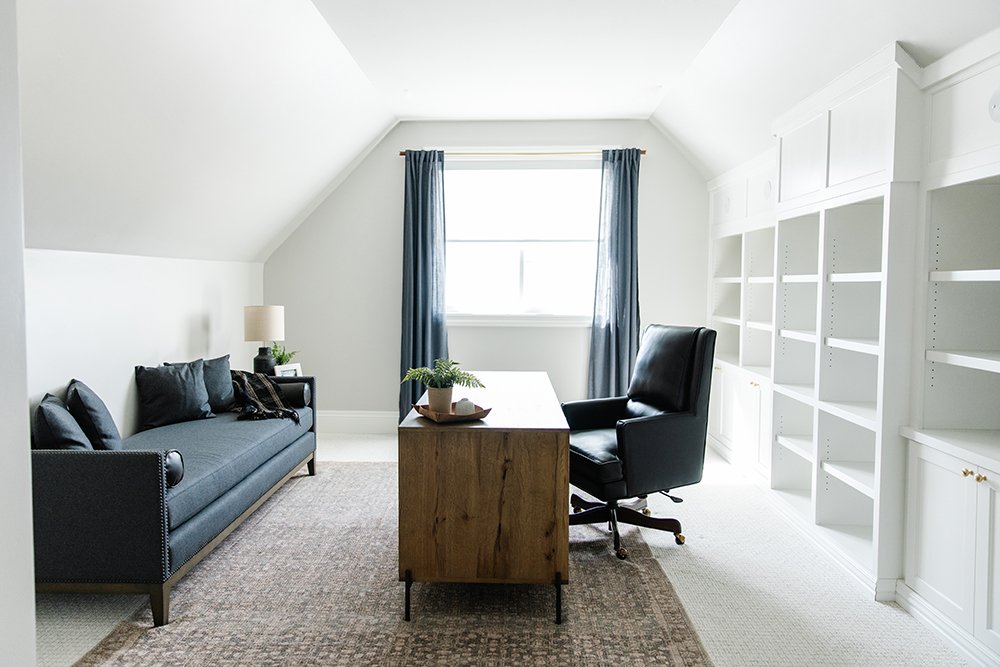  This office space in an upper-level room could feel small with the shorter ceiling, but Liz Powell uses her knowledge to open the space with built-in shelves and elongated furniture. Low ceiling attic office office built-ins #atticoffice #officebuil