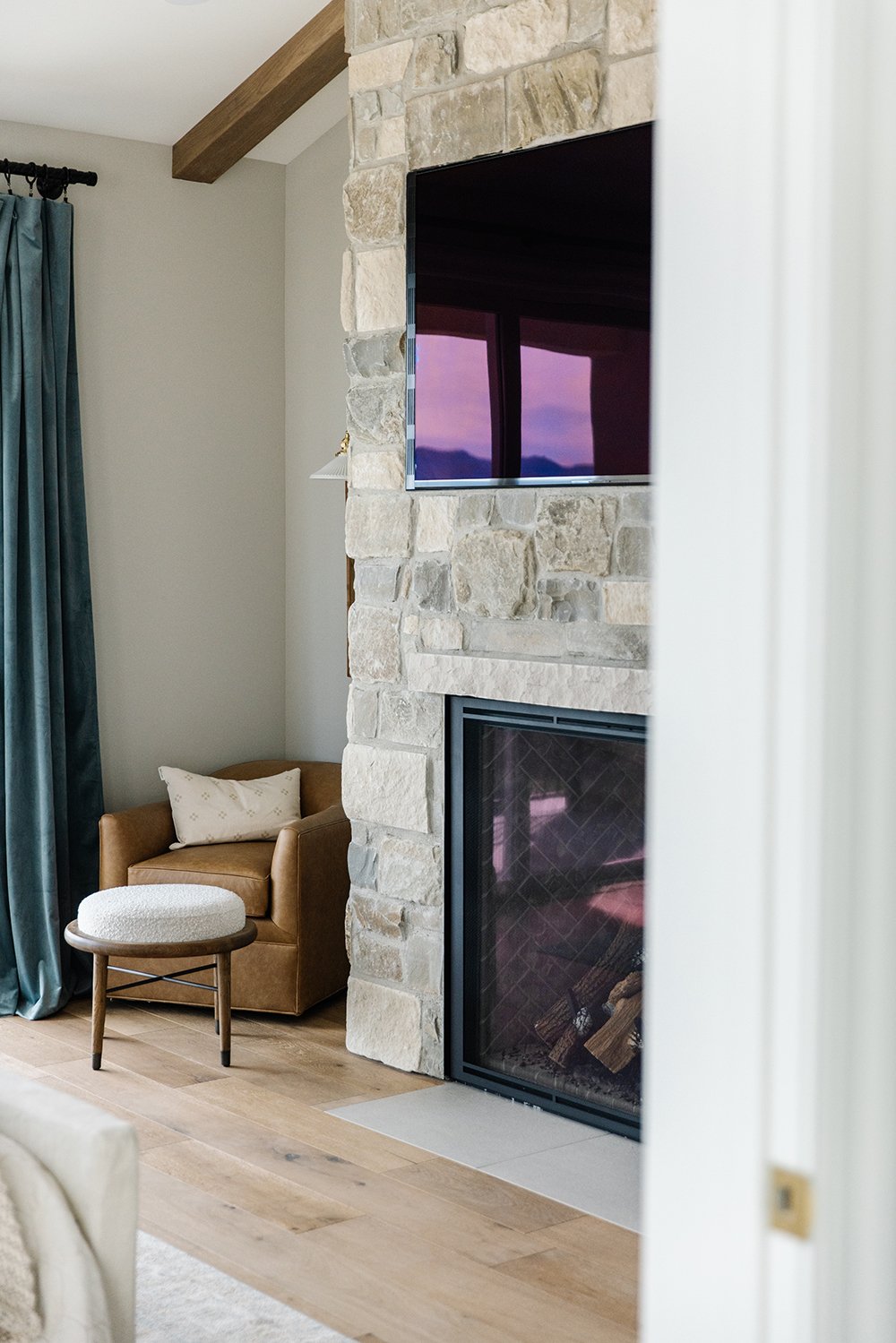  The subtle browns in the rock on this fireplace tie into the brown of the exposed beam and the chair below. Exposed beams vaulted ceilings stone fireplace #lizpowell #exposedbeams #accentchair #neutralfireplace 