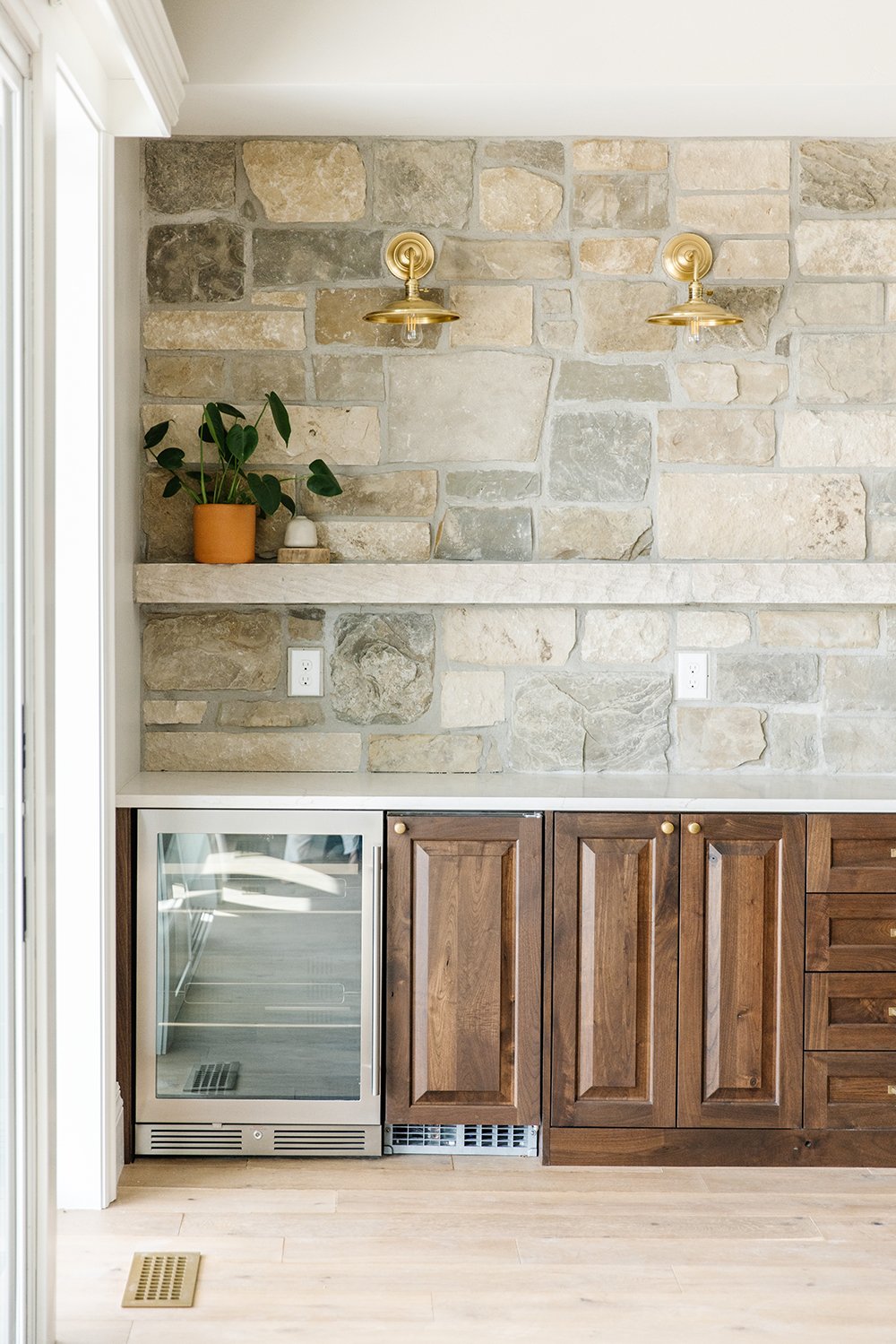  Using the rock as a backsplash in this area follows the house's theme. The golden sconces pair well with the golden handles on the cabinetry. Stone backsplash gold sconce kitchenette #stoneaccentwall #goldensconce #stoneshelf #kitchenette 