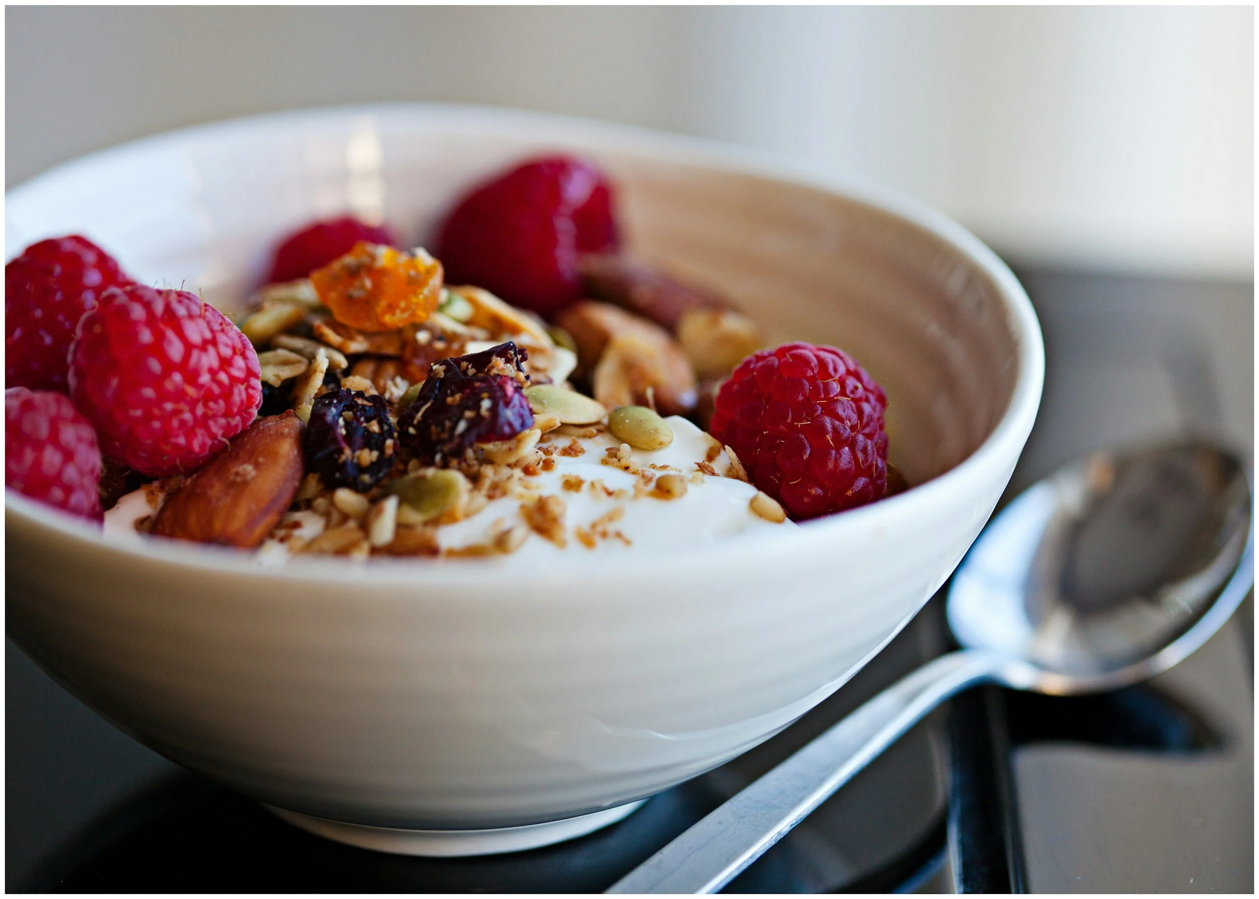 A bowl of full-fat Greek yoghurt topped with fresh raspberries, a high-protein, low-sugar breakfast recommended by nutritionist Caren Richards to support blood sugar balance during perimenopause
