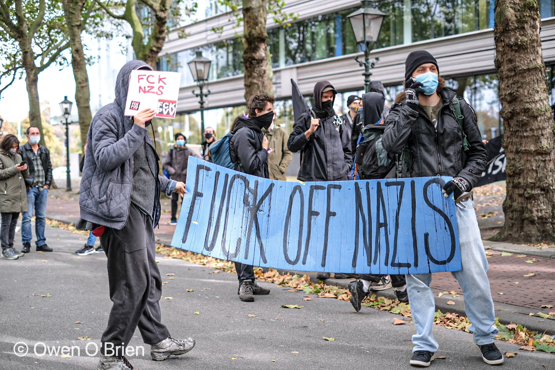 Tegenstanders van de rechts-extremistische beweging Nederlandse Volks-Unie (NVU) staan met spandoeken lijnrecht tegen de groep tijdens het lopen van hun mars in Den Haag (oktober 2020). 