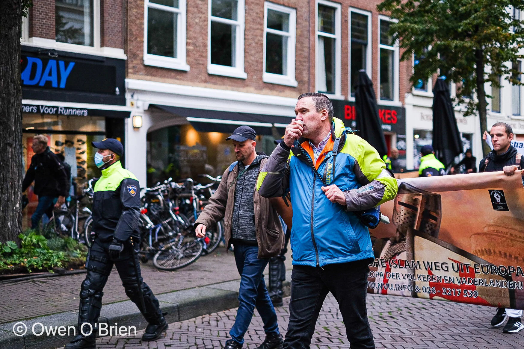 De rechts-extremistische beweging Nederlandse Volks-Unie (NVU) loopt onder begeleiding van de ME over de Herengracht in Den Haag (oktober 2020).