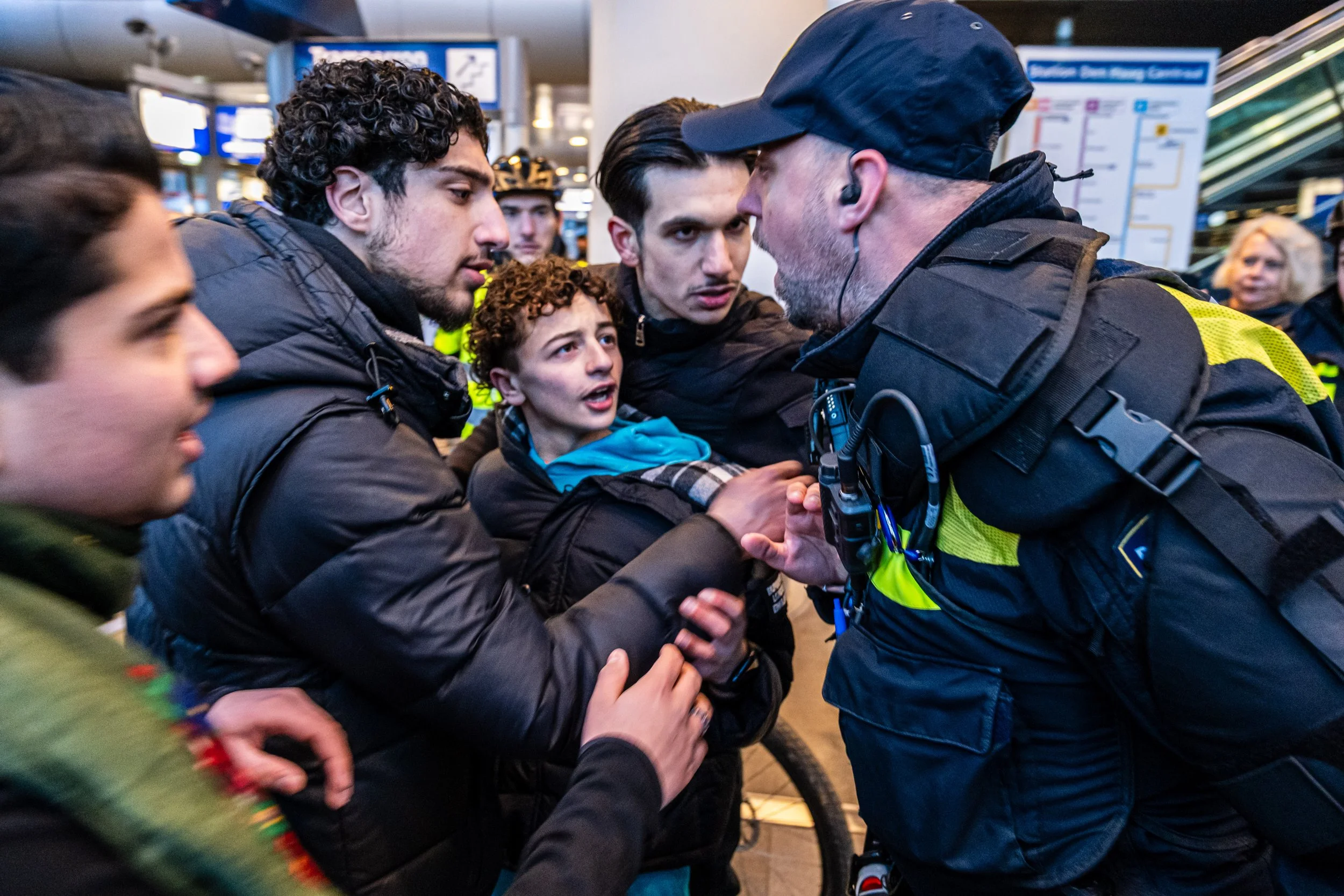 Een agent van de Mobiele Eenheid spreekt demonstranten aan nadat de politie heeft ingegrepen op een treinstation in Den Haag (februari 2026).