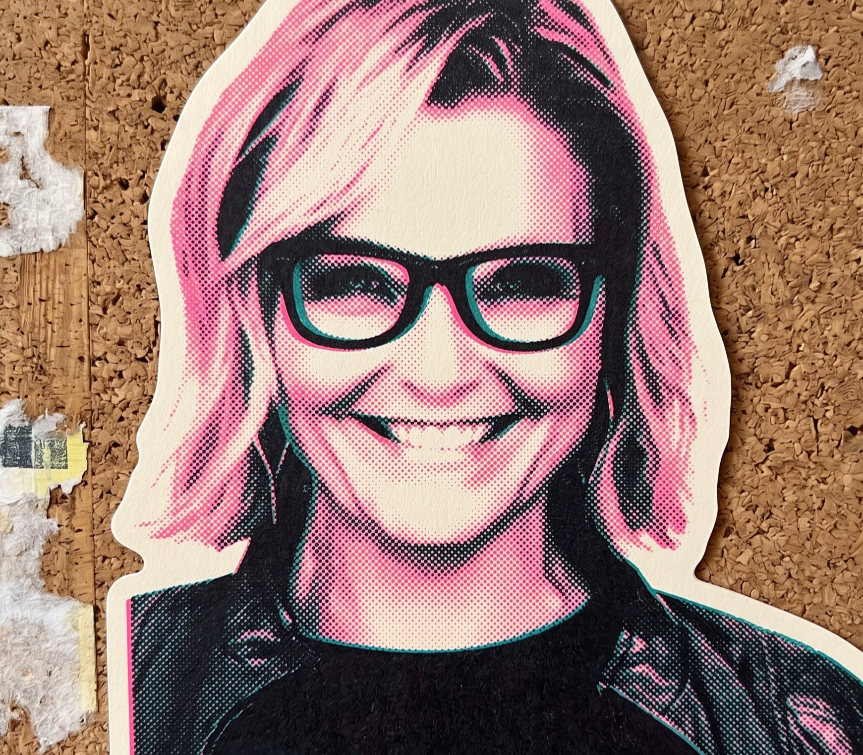 A stylized caricature of a woman wearing glasses and smiling, with blonde hair and a black shirt, on a corkboard background.