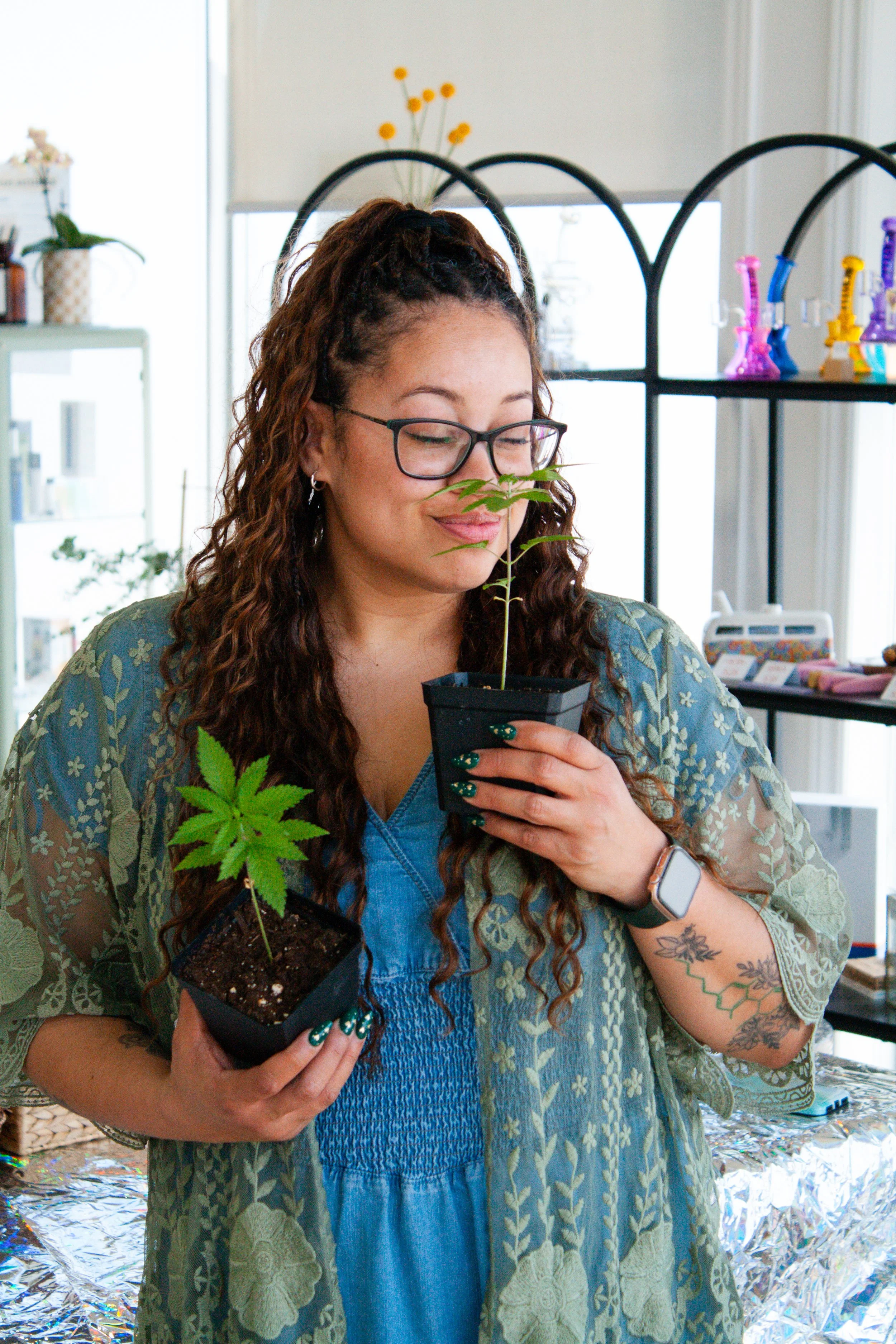 Tiffany, regional store manager, in a green throw holding her homegrown cannabis clones from Carmel’s Animal Face strain.