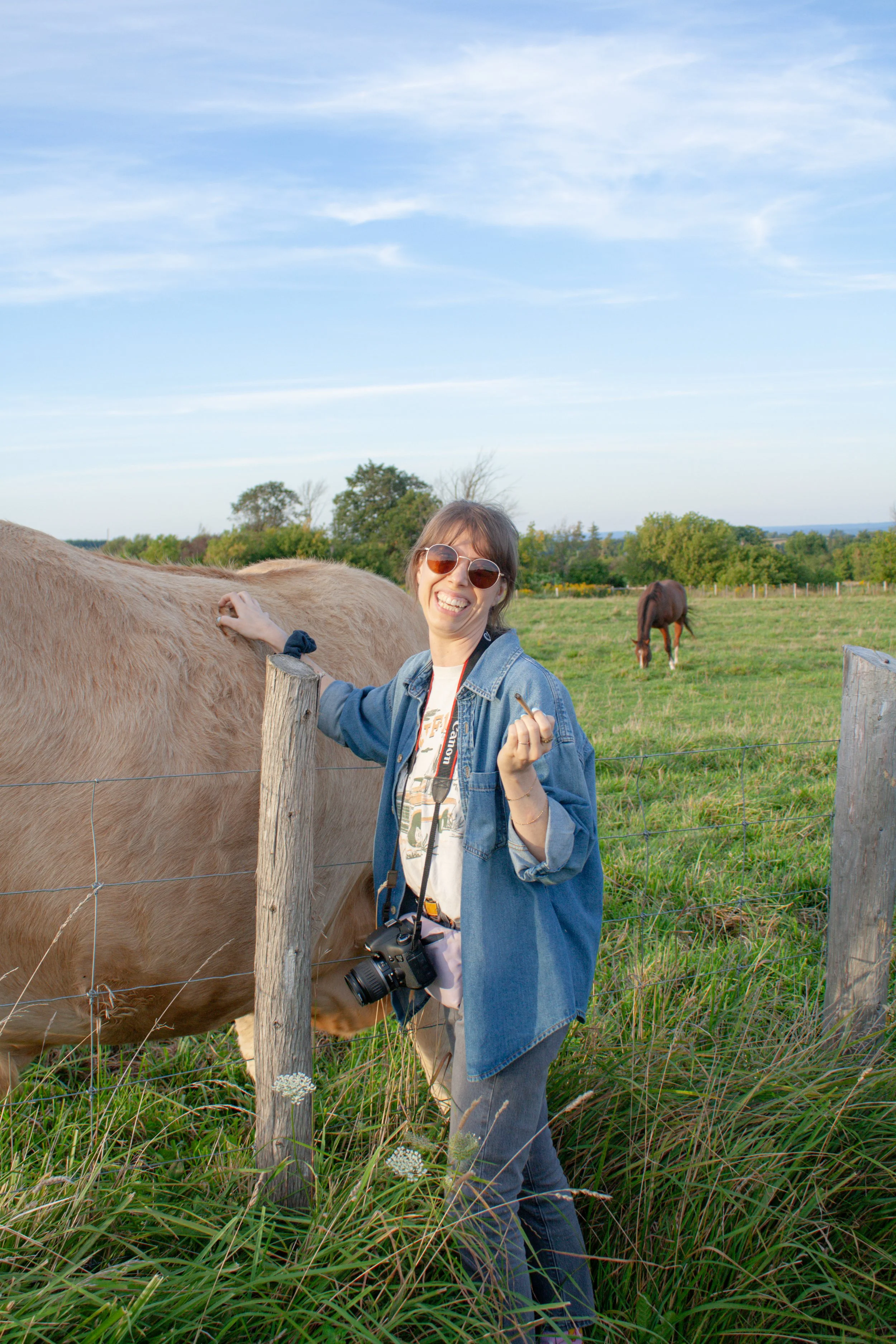 Quinn, Prairie and Luna co-owner, joyfully smoking a joint at Purple Hills Cannabis Farm while petting a giant cow.