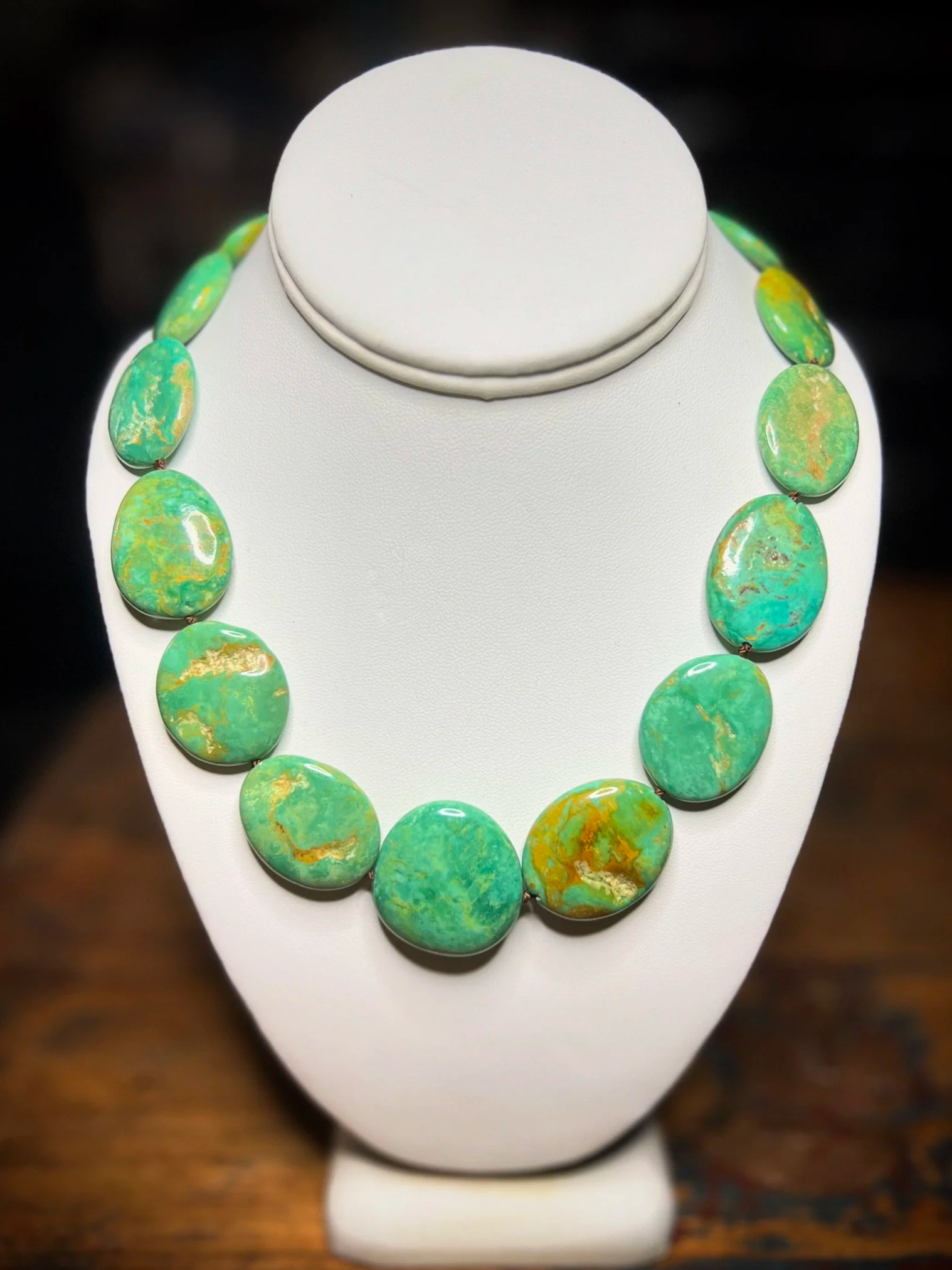 Turquoise stone necklace with large oval stones displayed on a white necklace stand.