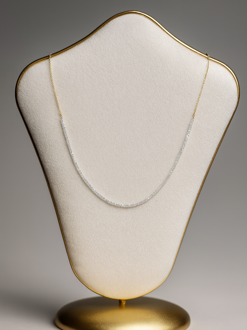 A diamond necklace displayed on a jewelry stand with a gold edging and base.
