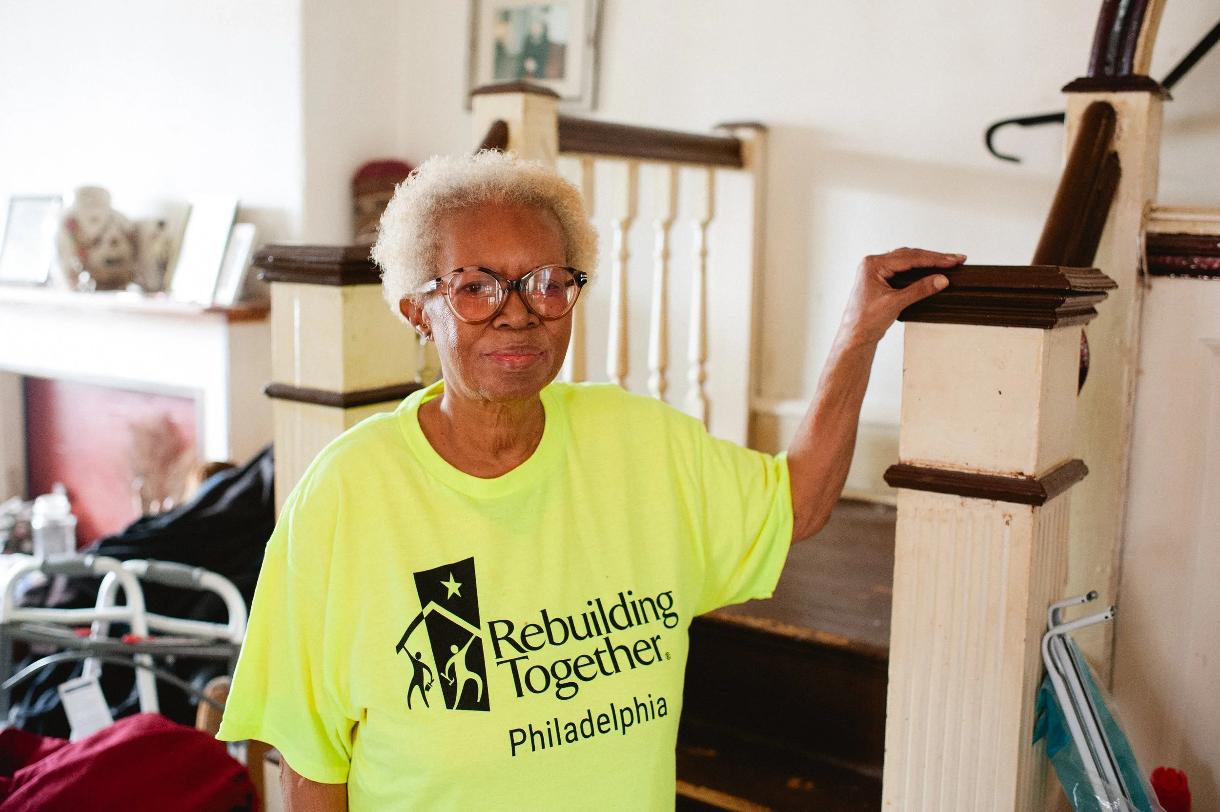 Homeowner smiling with her hand resting on the handrail of a staircase inside her house.