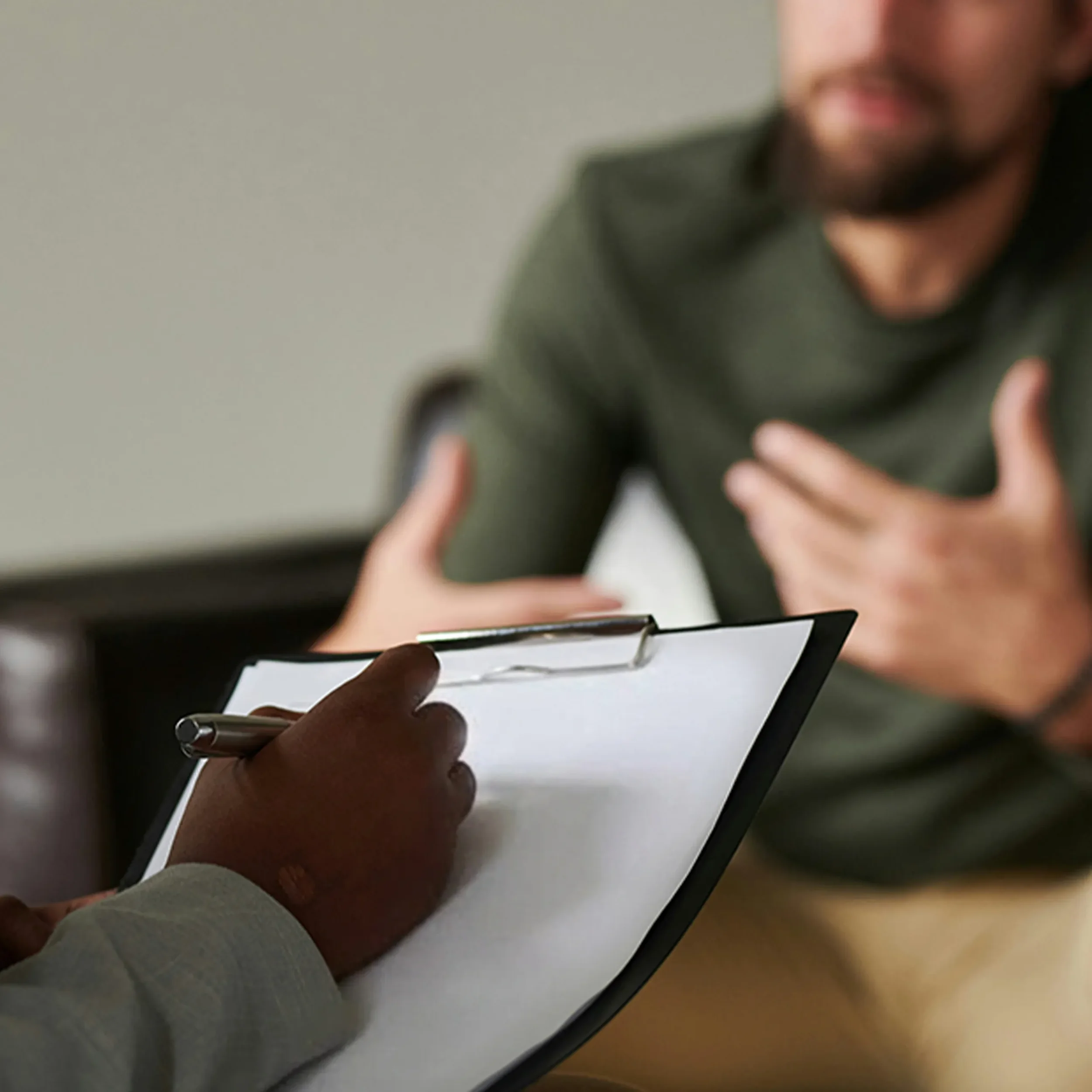 Unrecognizable female JTSN therapist takes notes while meeting with her journalist patient.