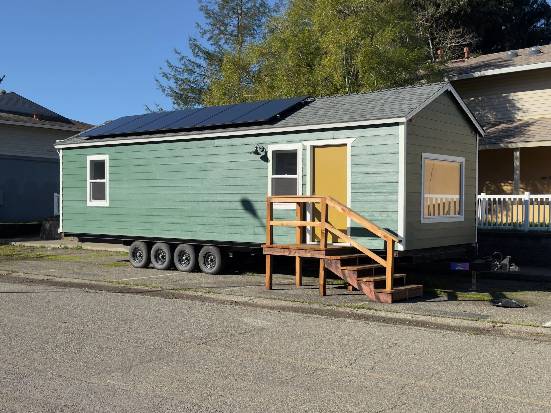 Image of a green tiny home with a yellow door.