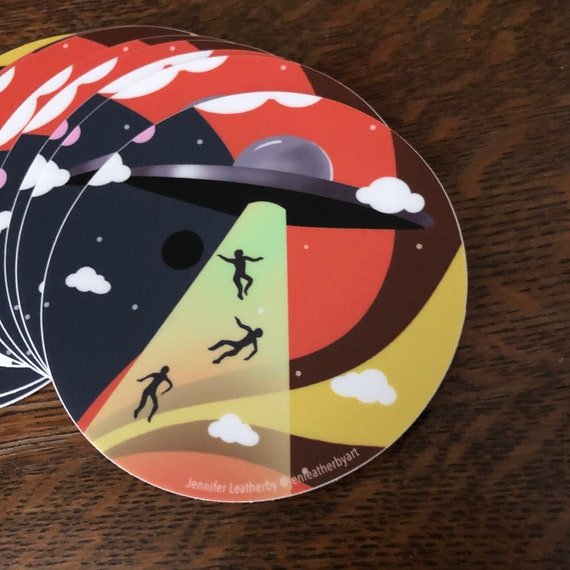 3-Inch Round Sticker Of A Silver UFO Beaming Up 3 People In Front Of A Psychedelic Sky.