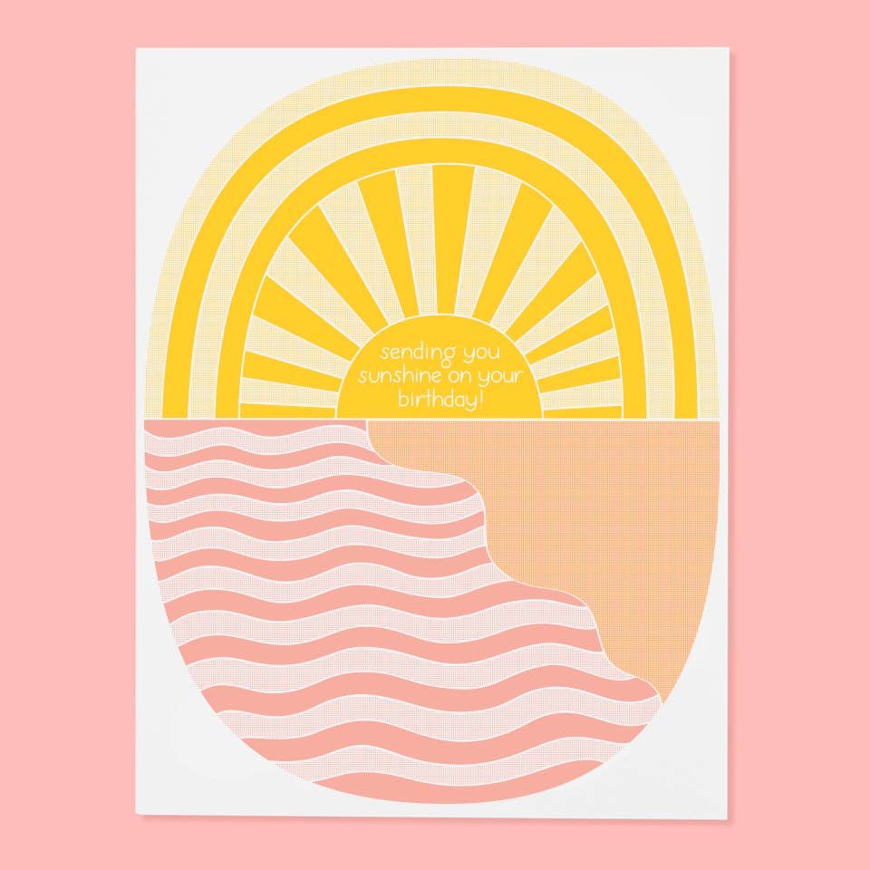 Image Of Illustrated Greeting Card With Vintage Woodcut-Style Yellow Sun Above Pink Woodcut-Style Waves. Hand-Drawn Type On The Sun Center Reads “Sending You Sunshine On Your Birthday”