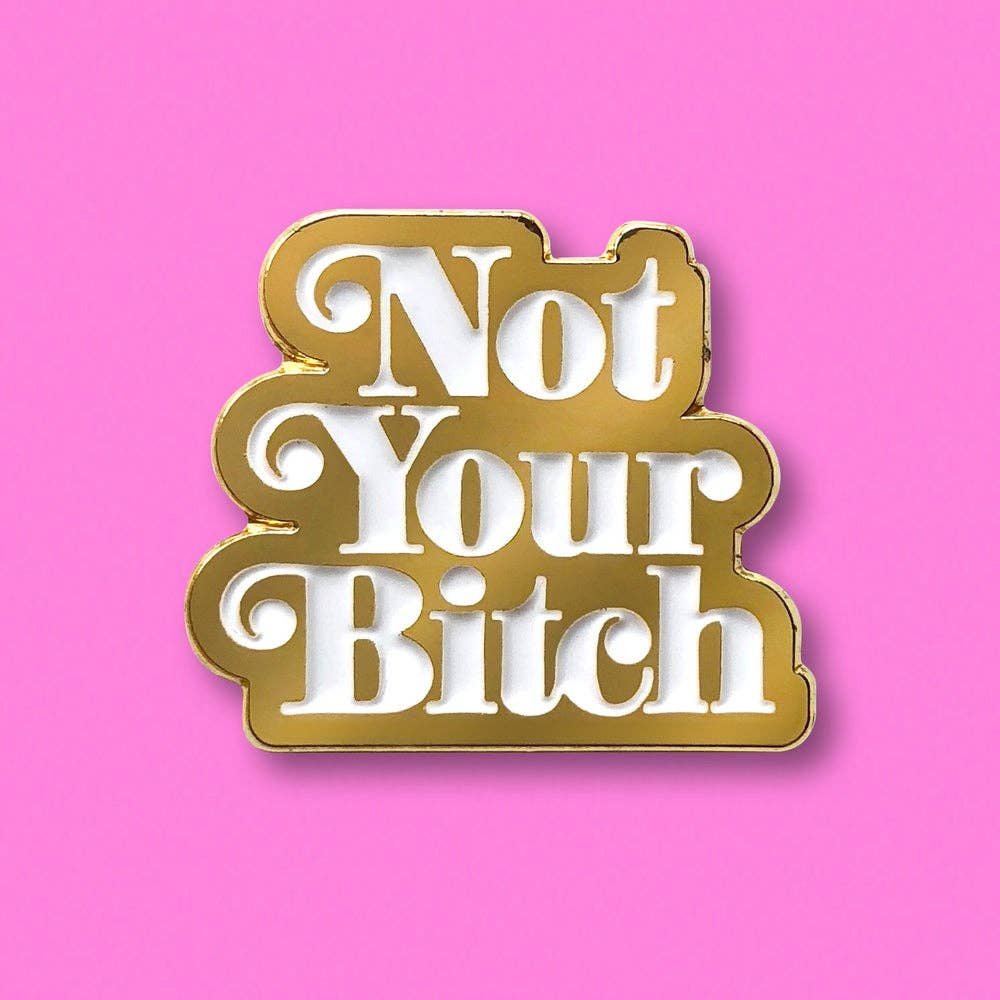 Not Your Bitch Gold Enamel Pin With White 70’s Style Type. Approximately 1.5 Inches Tall By 1 Inch Wide.