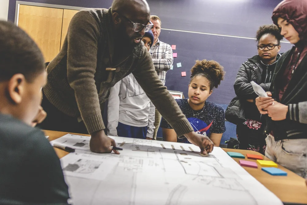 Students working over drawings at a table