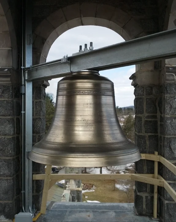 Large cast bronze church bell mounted inside a stone bell tower with a custom steel support system