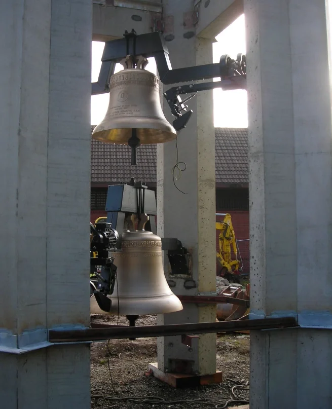 Bronze bells being professionally installed with custom mounting equipment inside a bell tower
