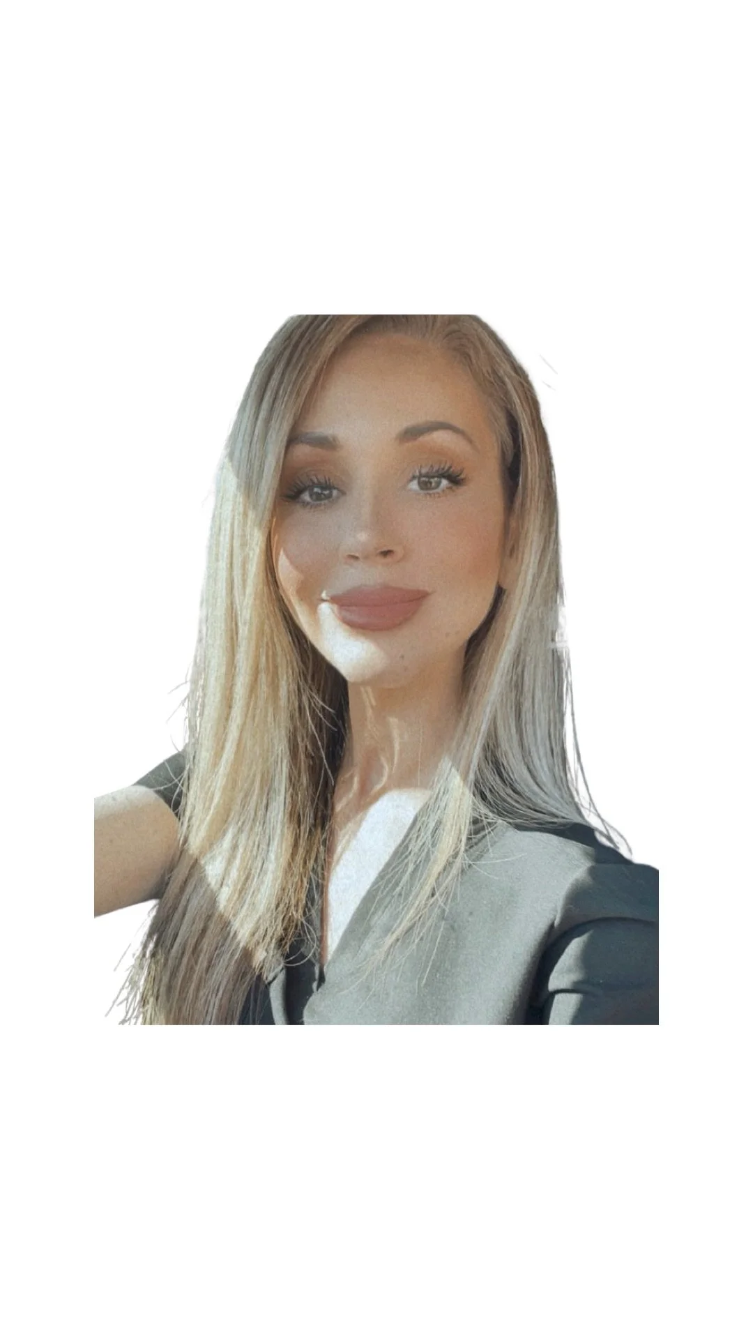 A woman with long blonde hair, makeup, and a slight smile takes a selfie against a plain white background.