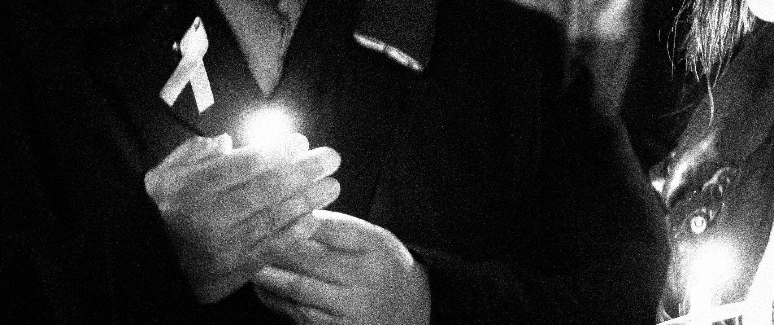 Hand cradling a lit candle with an AIDS ribbon in the background