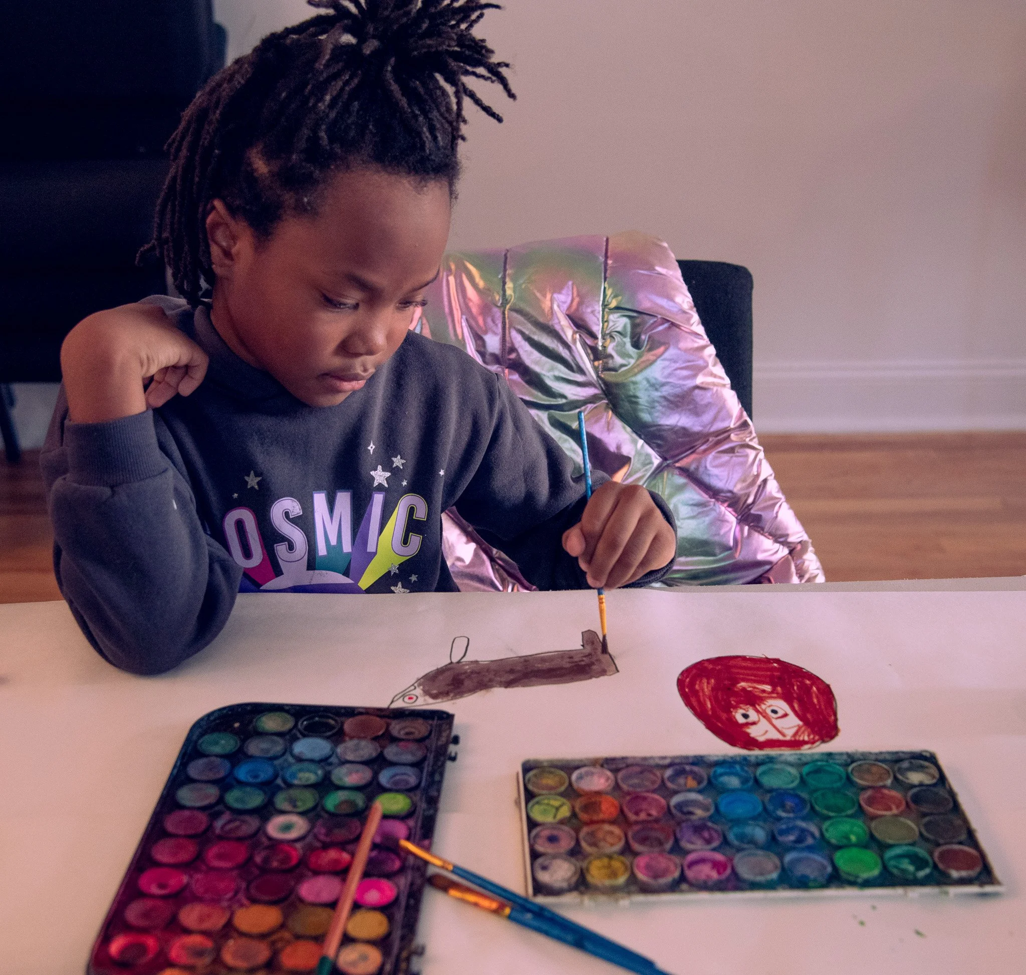 Young girl painting with watercolors during a Healing Connections session, using art as a way to express emotions and process grief.