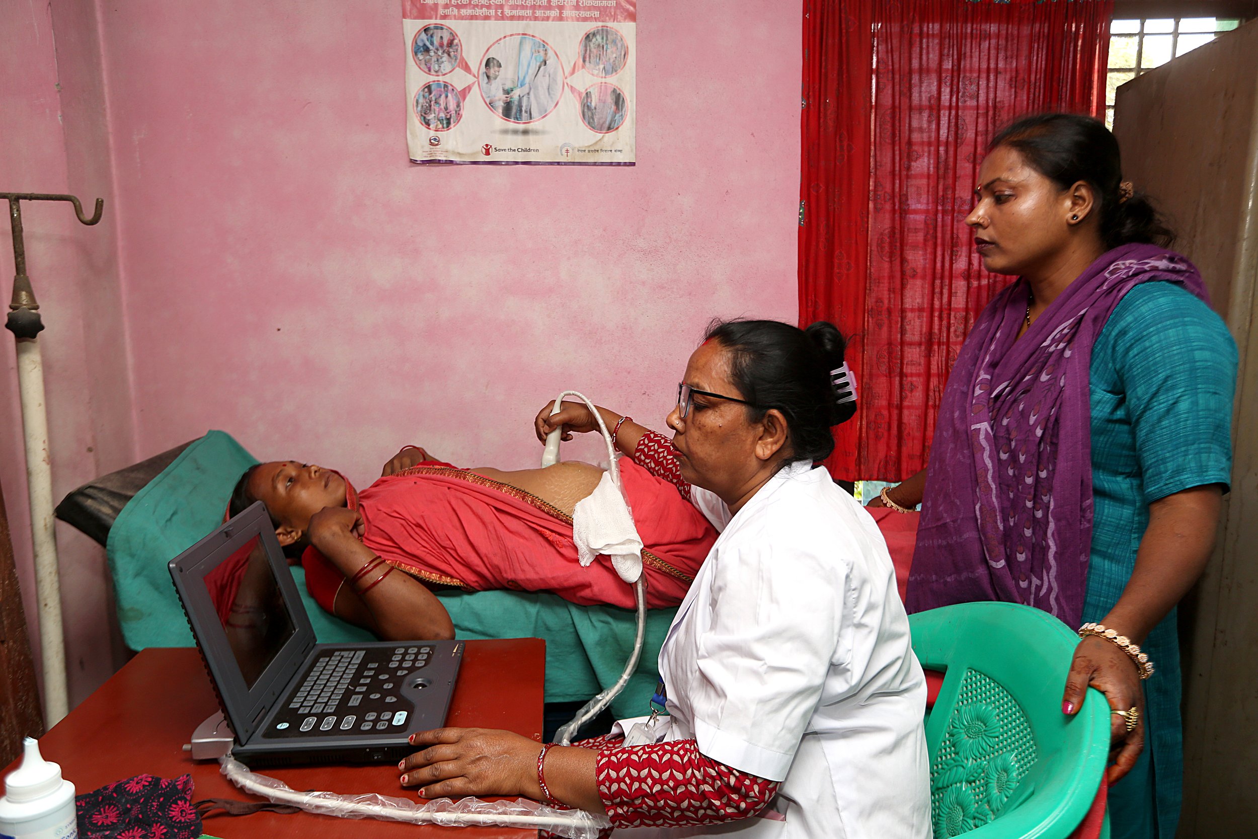 A health provider performs an ultrasound scan for an expectant mother at a health facility in Nepal as another woman looks on.