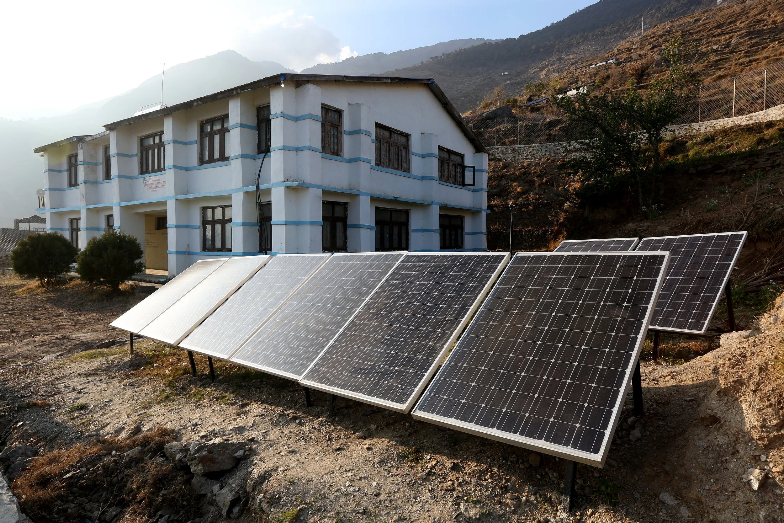 A solar panel array powers a rural health facility set against the mountains in Nepal.