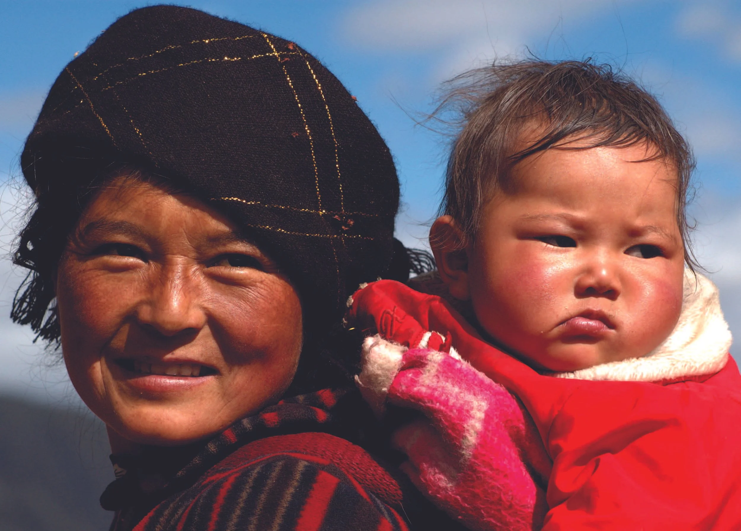 A Tibetan mother and her newborn outdoors in winter clothing