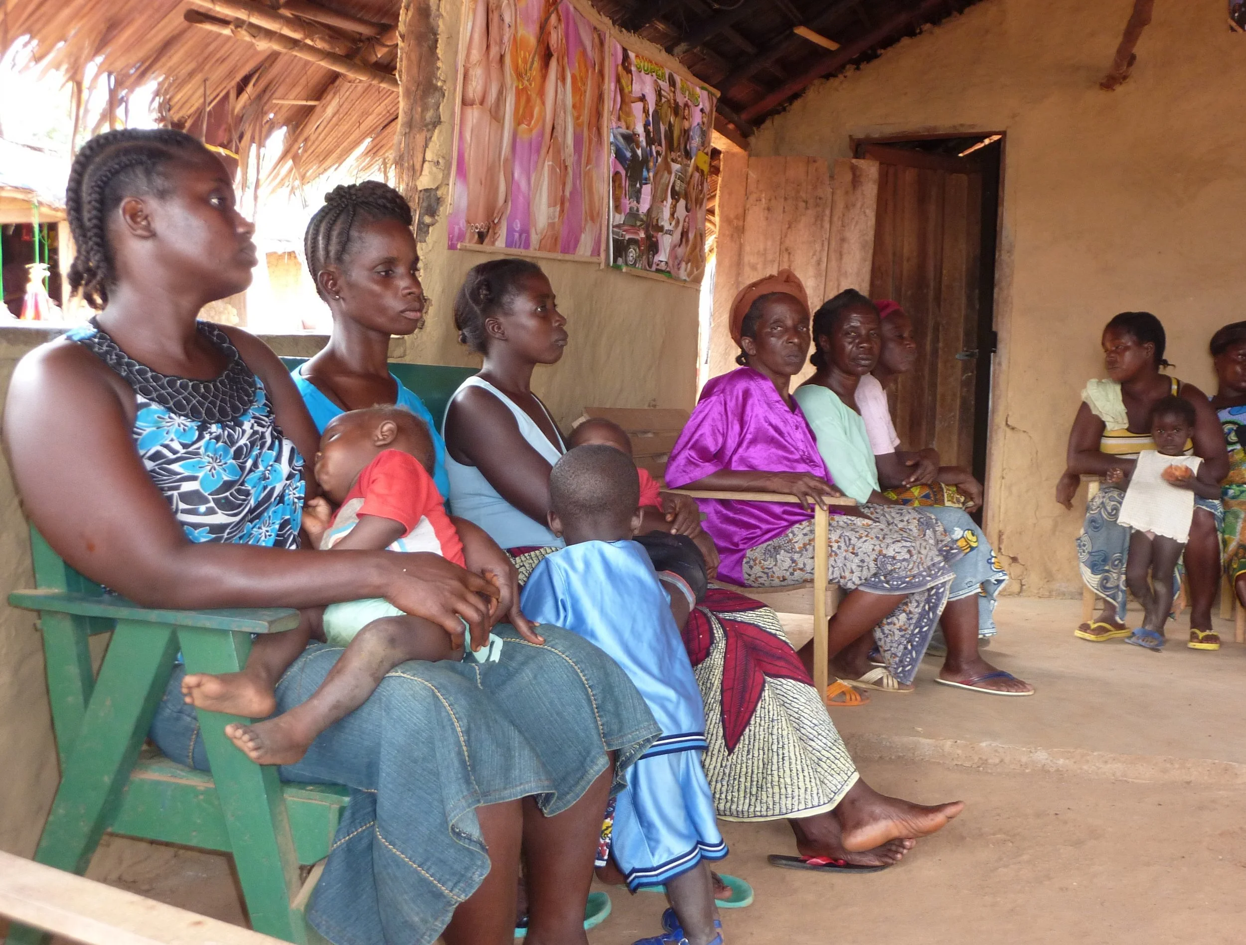 A photo of mothers and their children sitting outside of a health facility in Liberia.