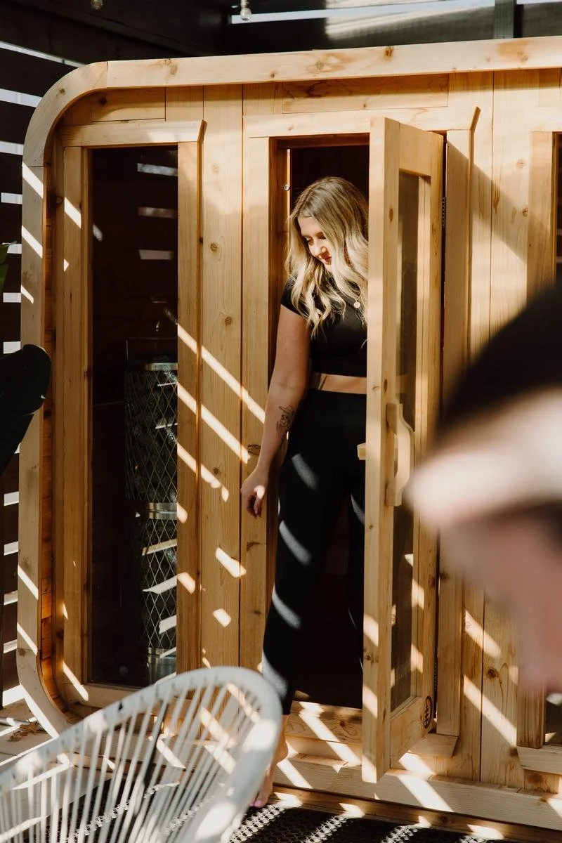 Woman entering infrared sauna cabin at ADAPT Tulsa wellness facility at ADAPT Tulsa, the wellness sister facility to Free Spirit Chiropractic