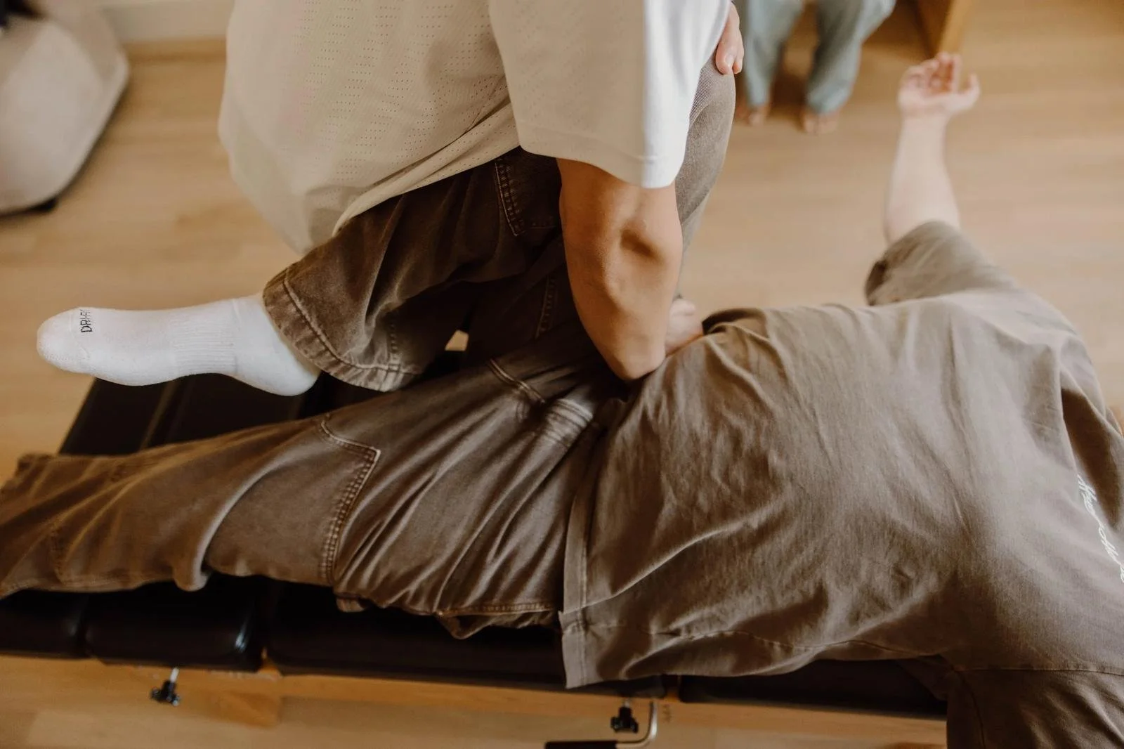 Male patient in prone position receiving full-body leg and hip adjustment — adult chiropractic adjustment in Tulsa