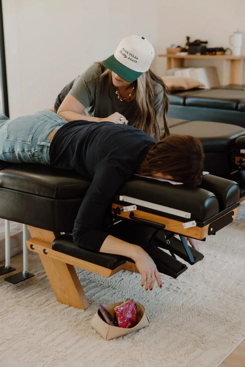 Dr. Lacey Nevel in cap adjusting male patient in prone position on chiropractic table — adult chiropractic adjustment in Tulsa