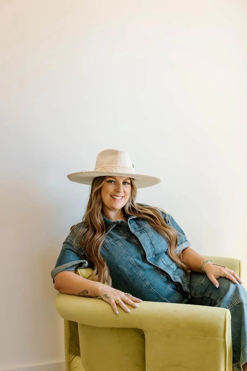 Dr. Lacey Nevel portrait seated in yellow velvet chair wearing cream wide-brim hat and denim — Free Spirit Chiropractic of Tulsa, Oklahoma