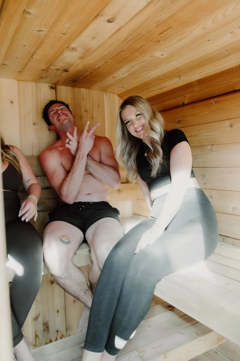 Couple sitting together inside wooden sauna at ADAPT Tulsa at ADAPT Tulsa, the wellness sister facility to Free Spirit Chiropractic