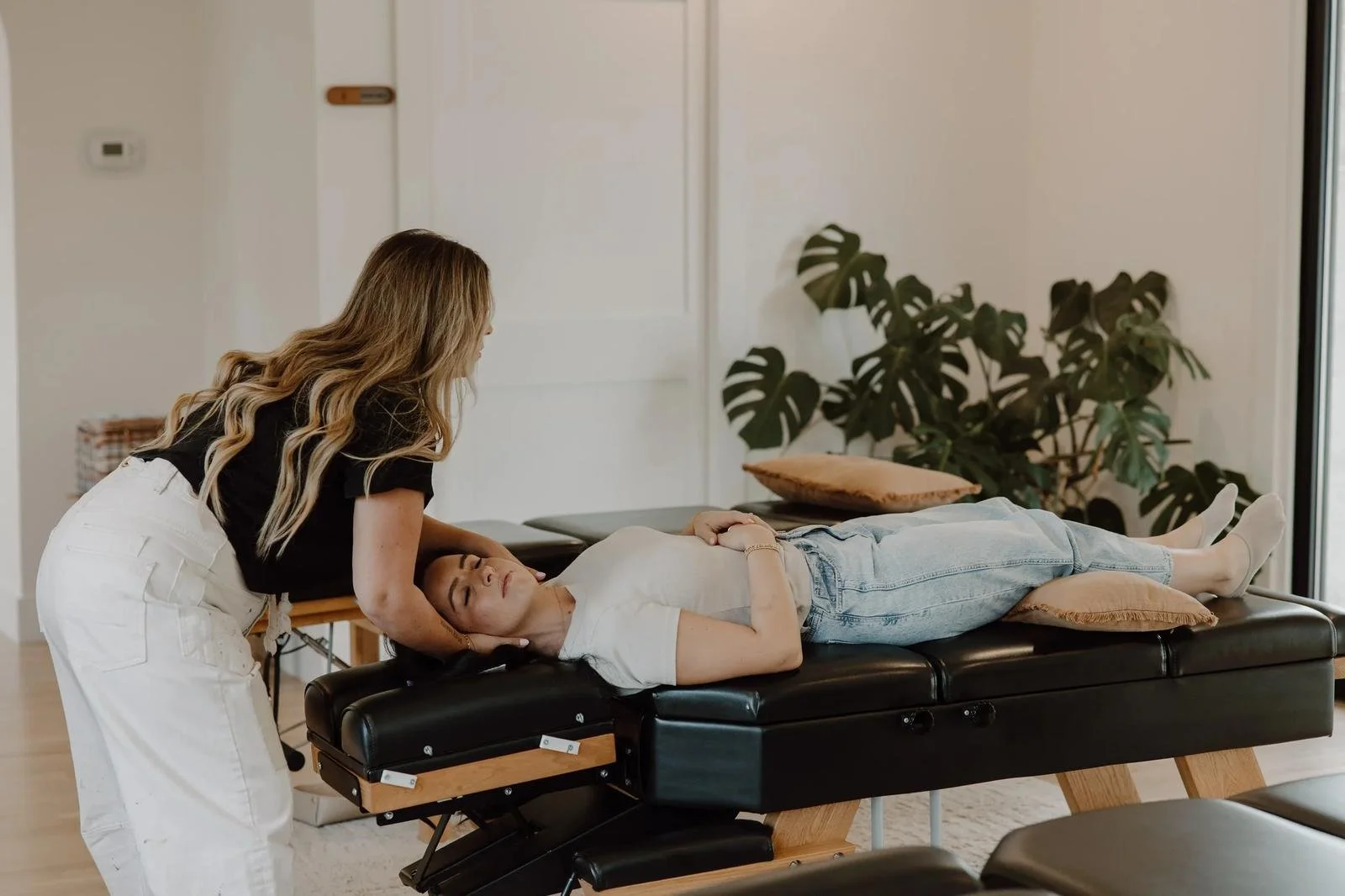Blonde practitioner adjusting young boy in blue shirt lying on table — pediatric chiropractor in Tulsa, Oklahoma