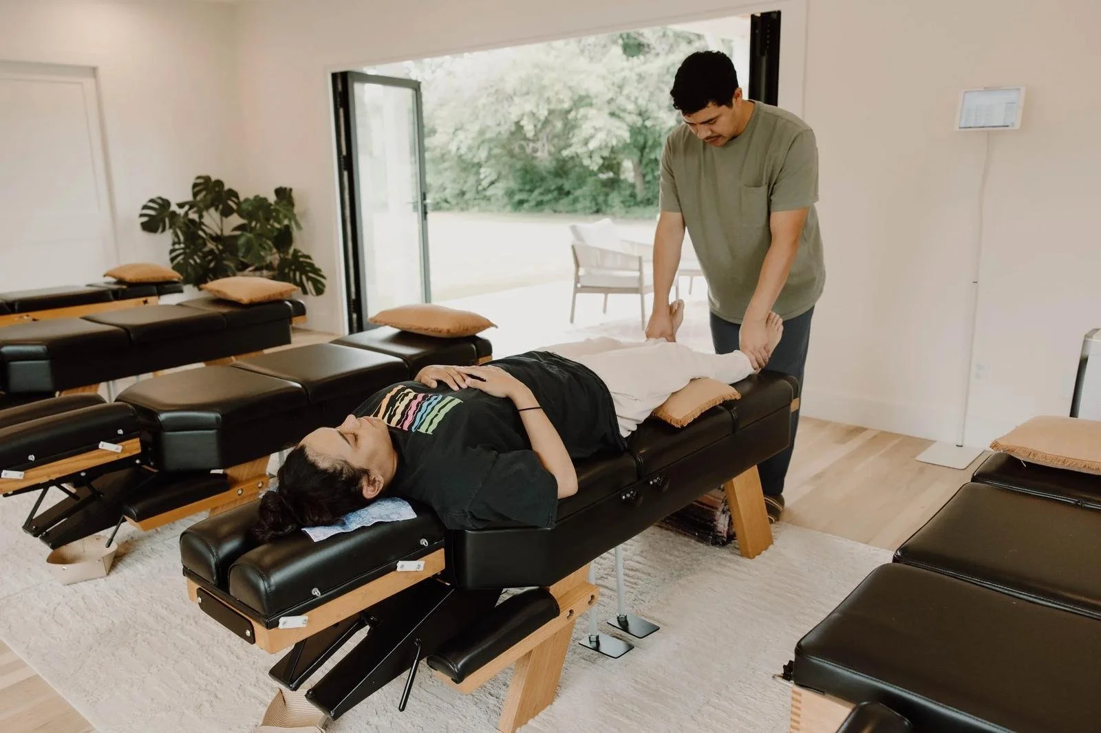 Dr. adjusting female patient on table in bright treatment room — postpartum chiropractor in Tulsa, Oklahoma