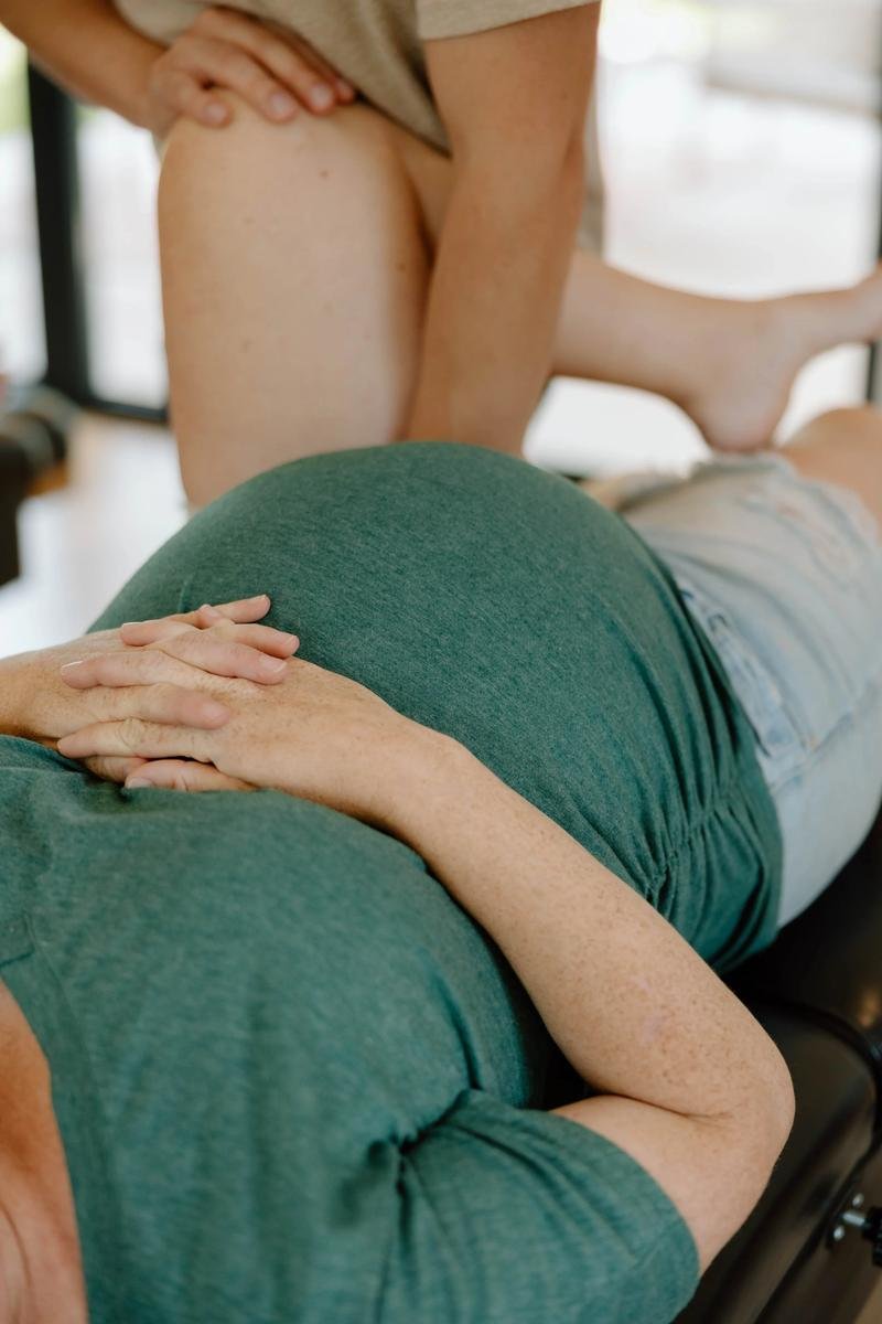 Pregnant patient in green top receiving side-lying pelvic adjustment, belly visible — prenatal chiropractic care in Tulsa, Oklahoma